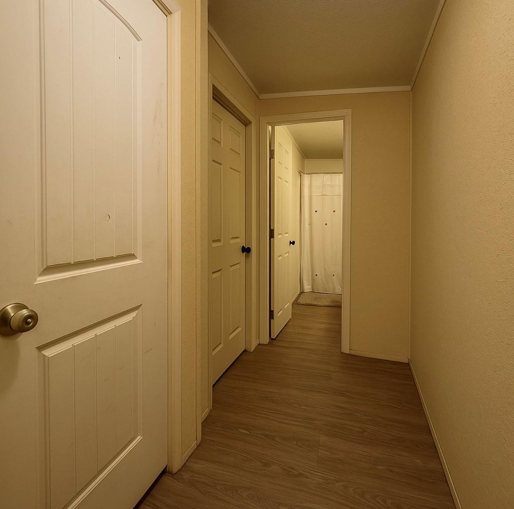 Corridor with dark wood-type flooring and crown molding