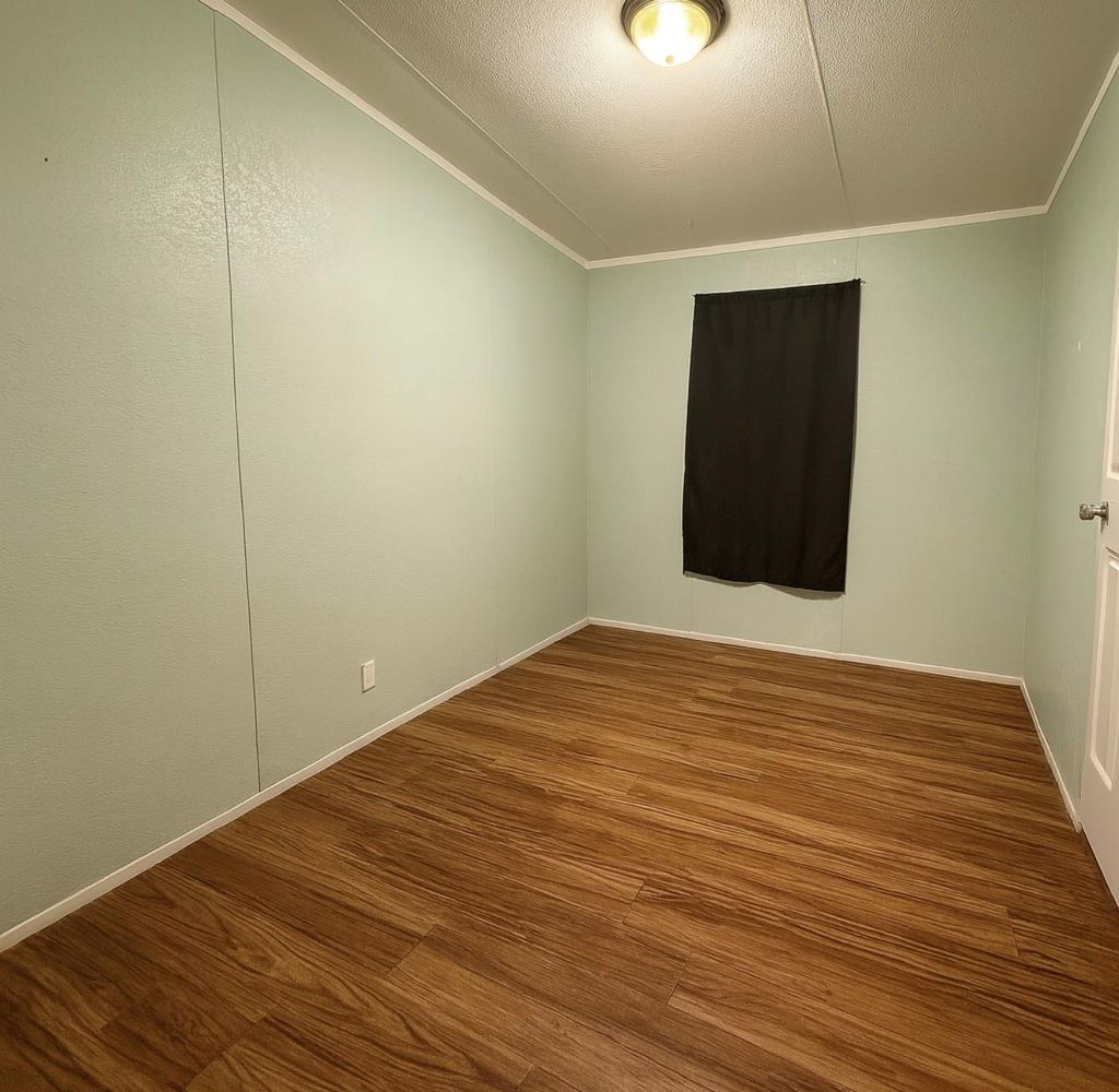 Empty room featuring ornamental molding, wood finished floors, and a textured ceiling