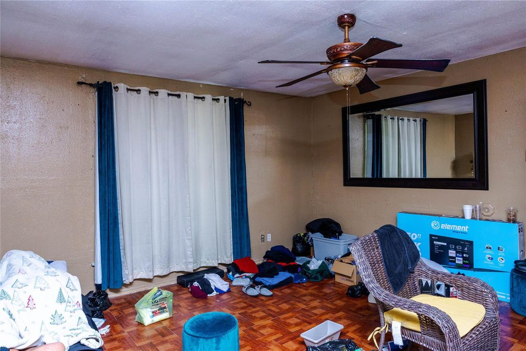 Bedroom with a ceiling fan, a textured wall, and a textured ceiling