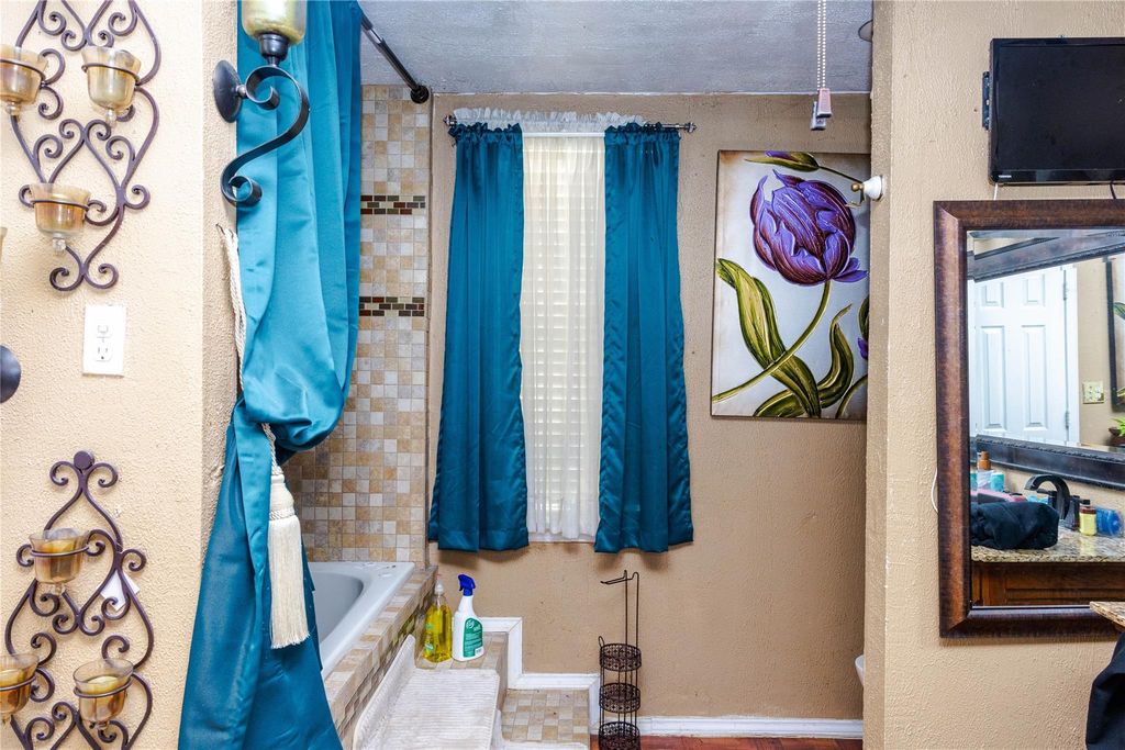 Full bath with a textured wall and shower / tub combo