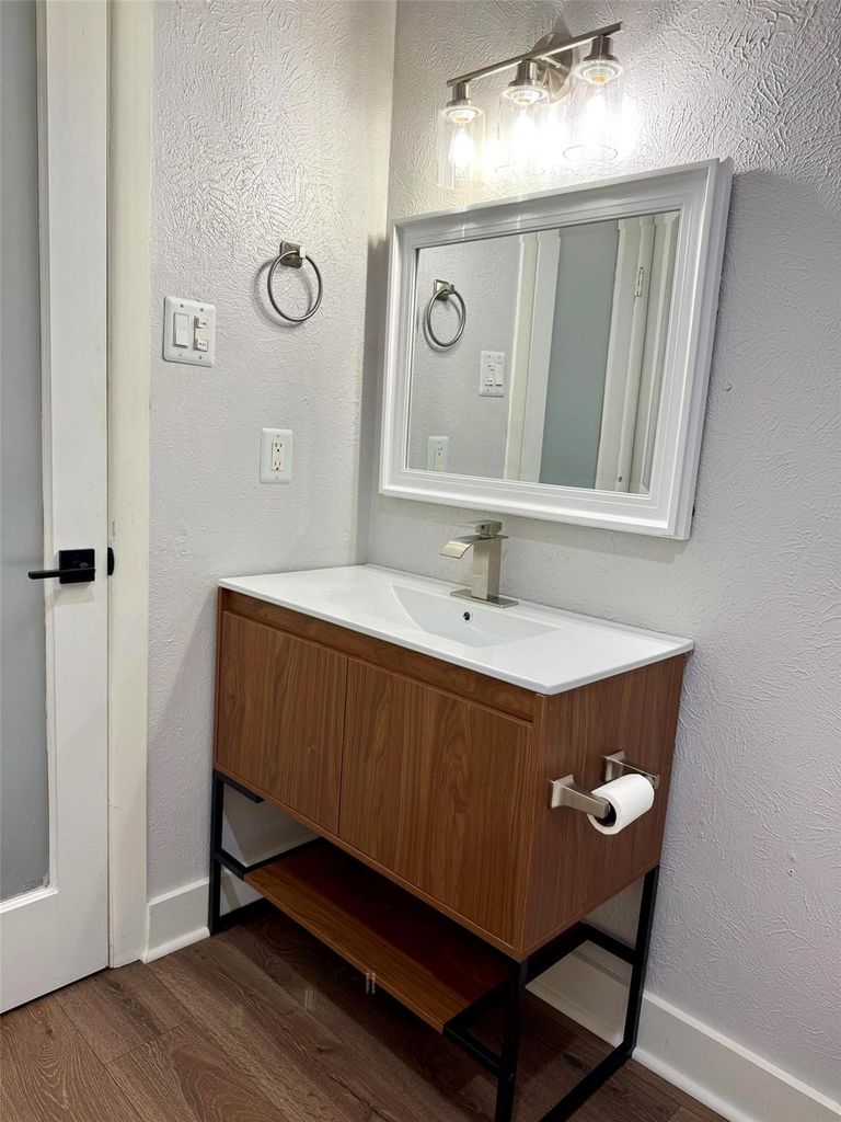 Bathroom featuring a textured wall, vanity, and dark wood-style floors