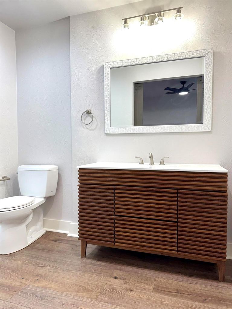 Bathroom featuring light wood-type flooring, vanity, and a textured wall