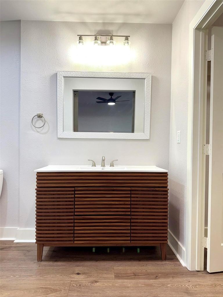 Bathroom view of vanity, wood finished floors, and a textured wall