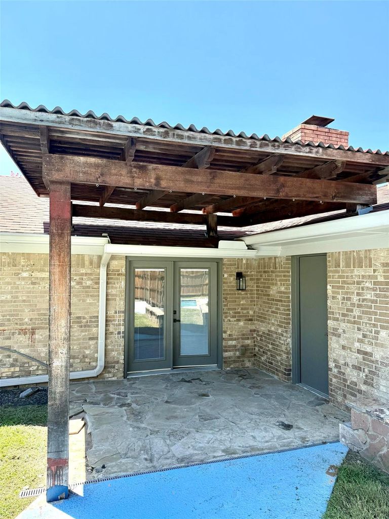 Entrance to property featuring a patio, brick siding, and french doors