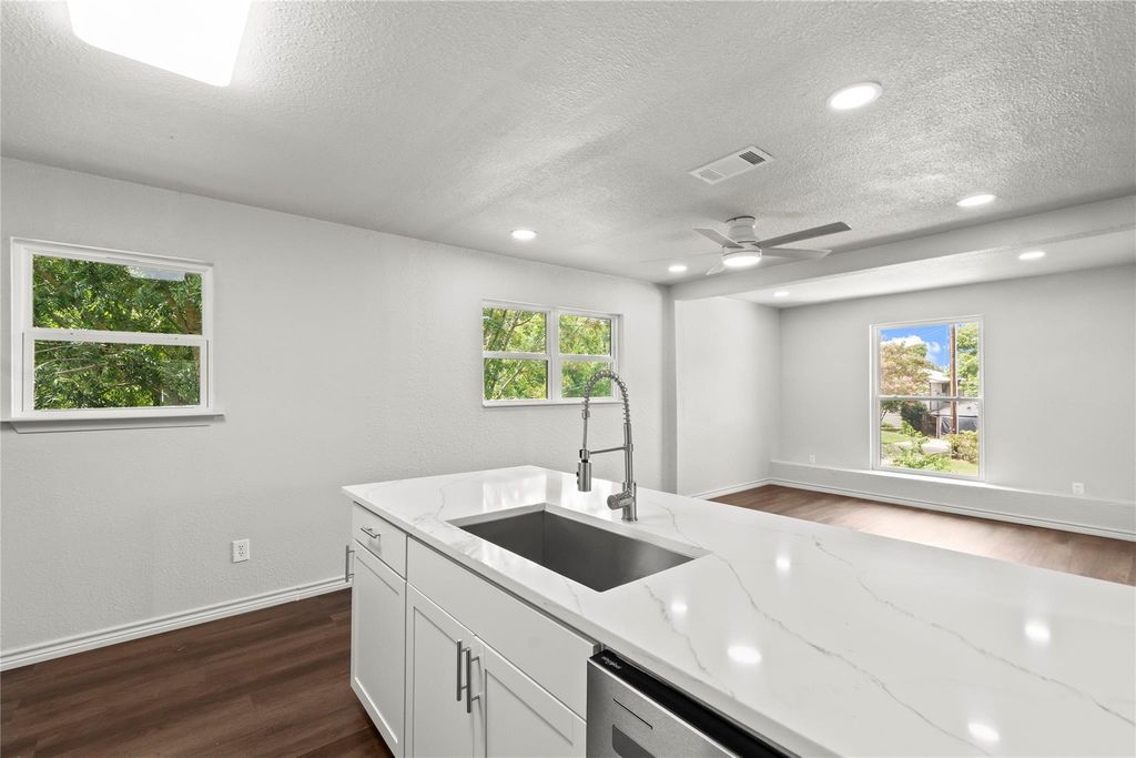 Kitchen with dark wood-style flooring, a textured ceiling, light stone counters, white cabinets, and recessed lighting
