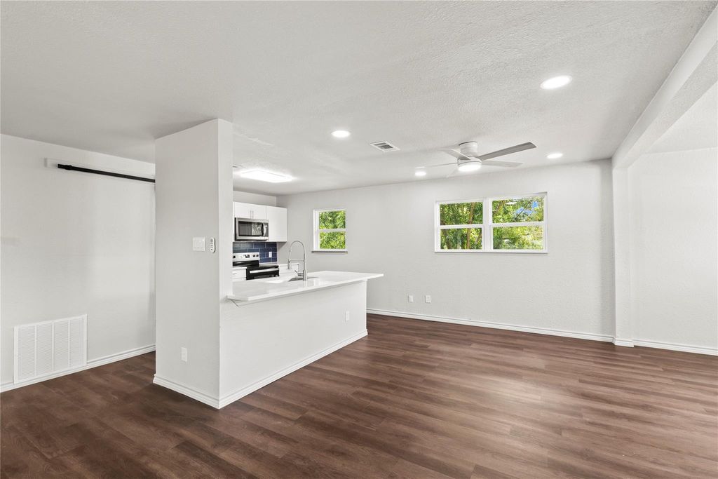 Kitchen featuring white cabinetry, dark wood finished floors, recessed lighting, appliances with stainless steel finishes, and a barn door