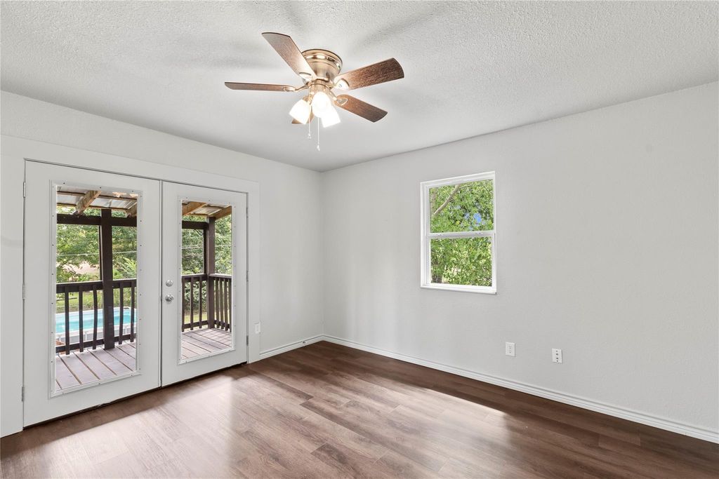 Spare room featuring wood finished floors, french doors, a textured ceiling, and a ceiling fan