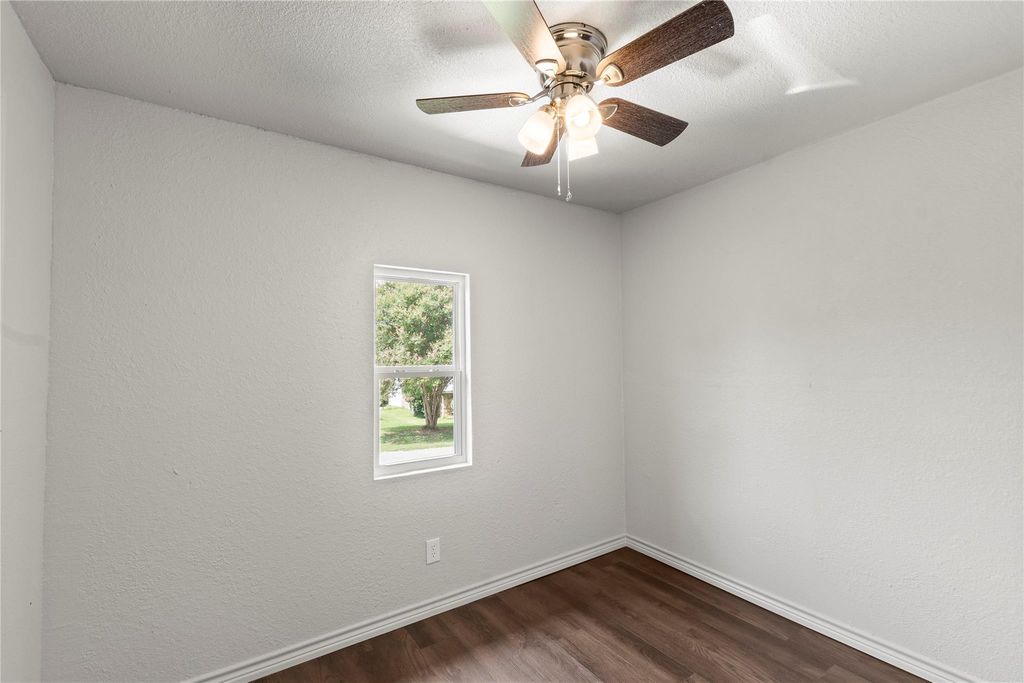 Unfurnished room featuring dark wood-style floors, a textured wall, a textured ceiling, and ceiling fan