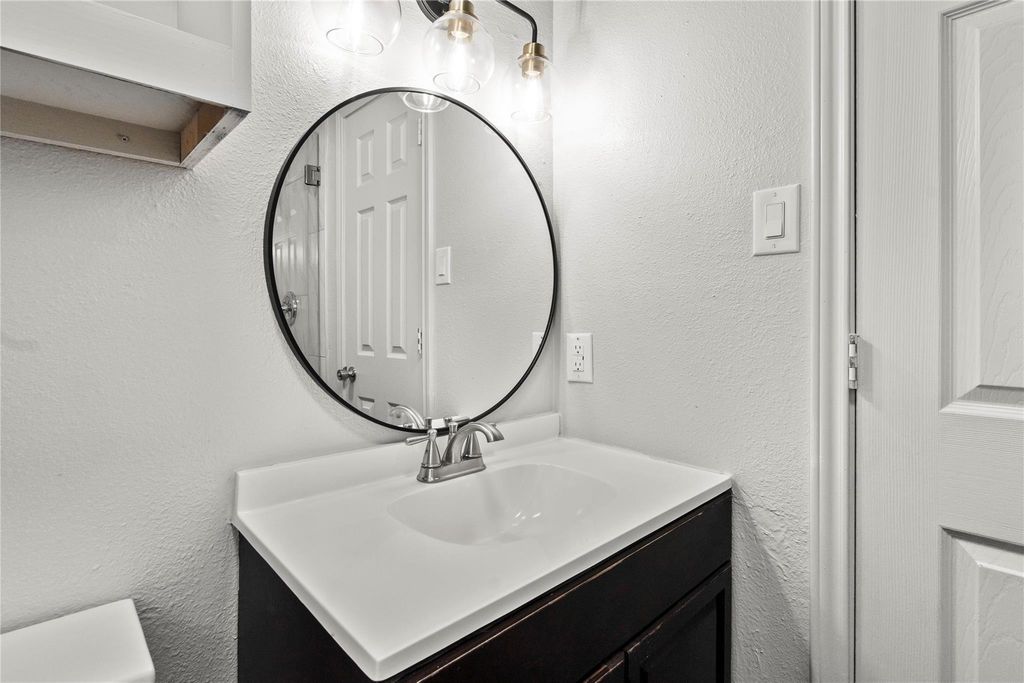 Bathroom with a textured wall and vanity