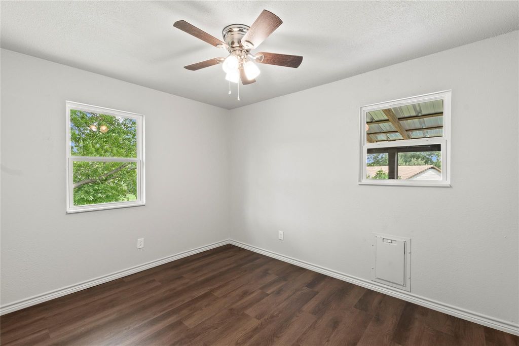 Spare room featuring dark wood-type flooring, ceiling fan, and a textured ceiling