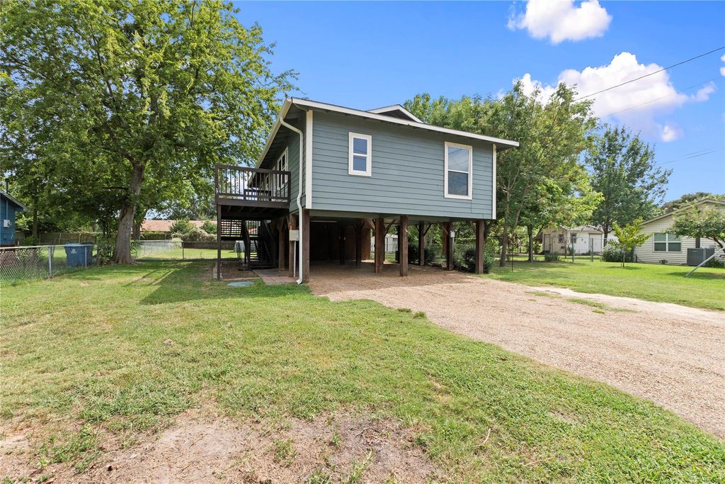 View of side of property with a carport, driveway, a wooden deck, stairway, and a patio