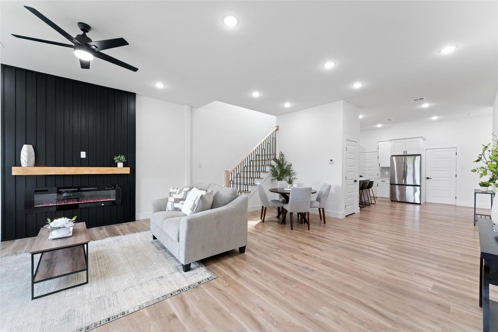 Living room featuring a glass covered fireplace, light wood finished floors, stairs, a ceiling fan, and recessed lighting