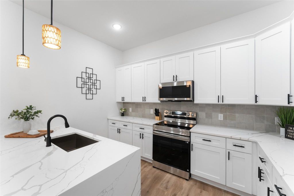 Kitchen with stainless steel appliances, light stone counters, white cabinetry, and recessed lighting