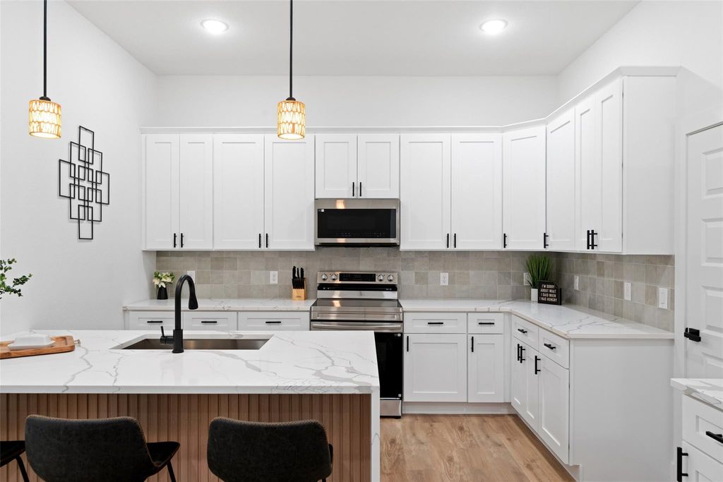 Kitchen featuring appliances with stainless steel finishes, light stone countertops, white cabinets, and recessed lighting