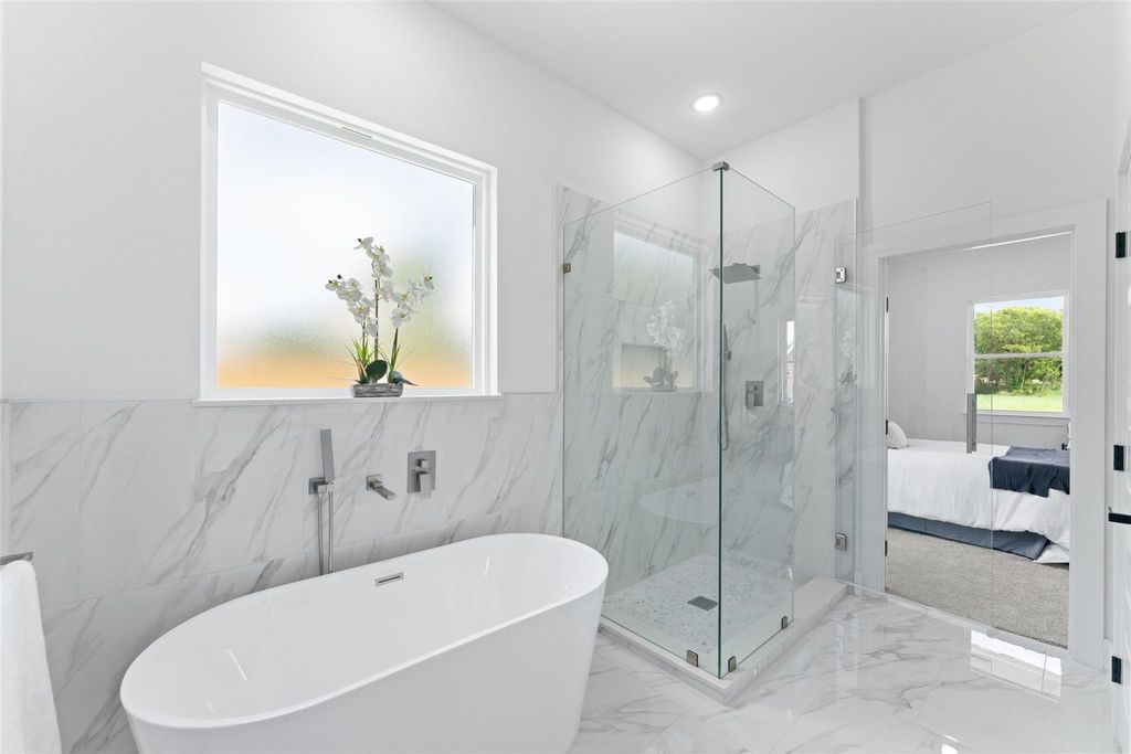 Ensuite bathroom with a freestanding tub, a marble finish shower, marble tiled floors, tile walls, and recessed lighting