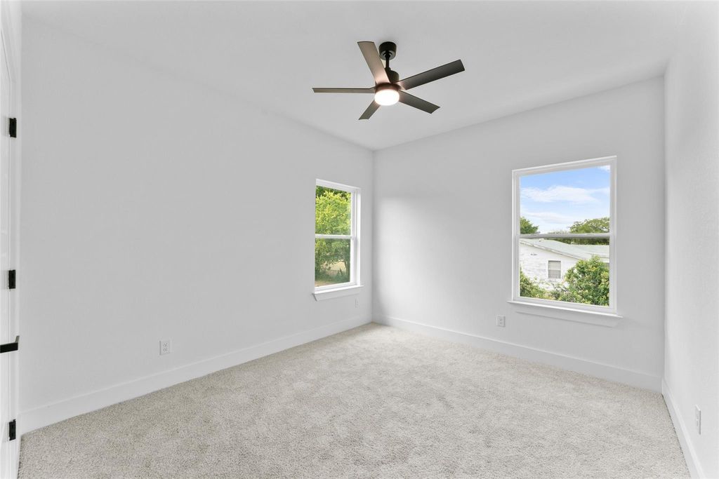 Empty room with light colored carpet, healthy amount of natural light, and ceiling fan