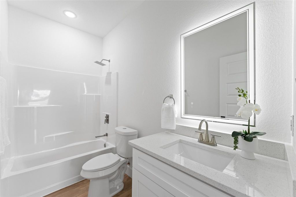 Full bath featuring bathing tub / shower combination, vanity, and light wood finished floors