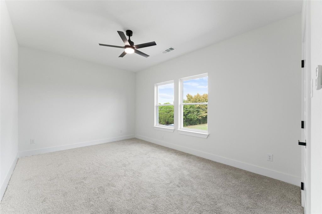 Unfurnished room with light colored carpet and a ceiling fan