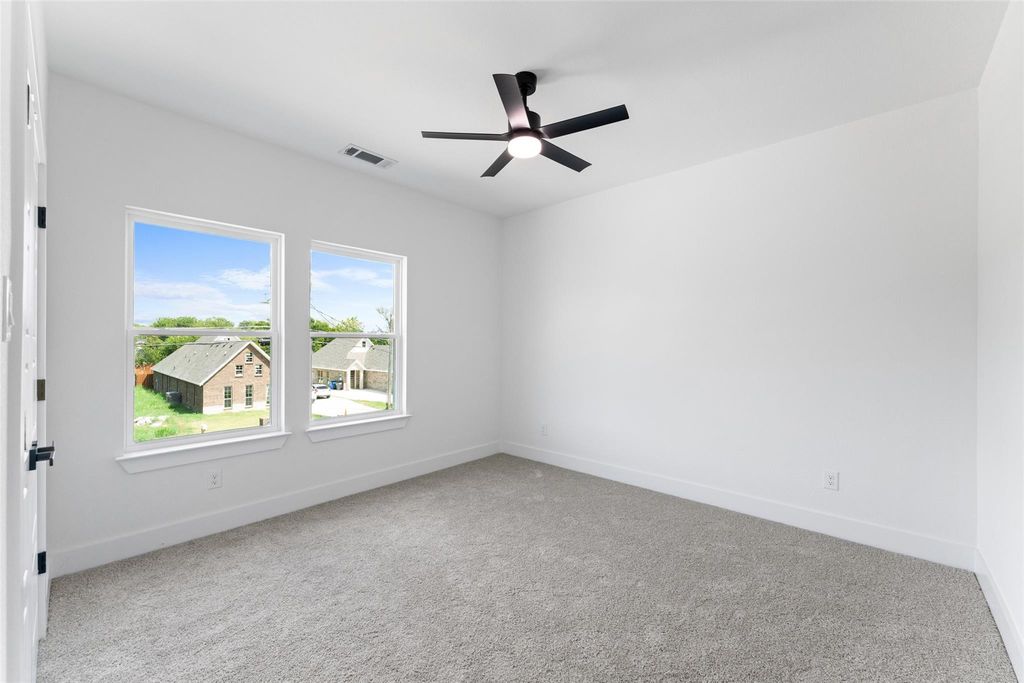 Empty room with light carpet and a ceiling fan