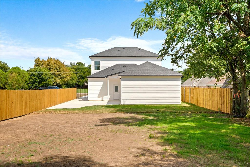 Rear view of property with a shingled roof, a patio area, and a fenced backyard