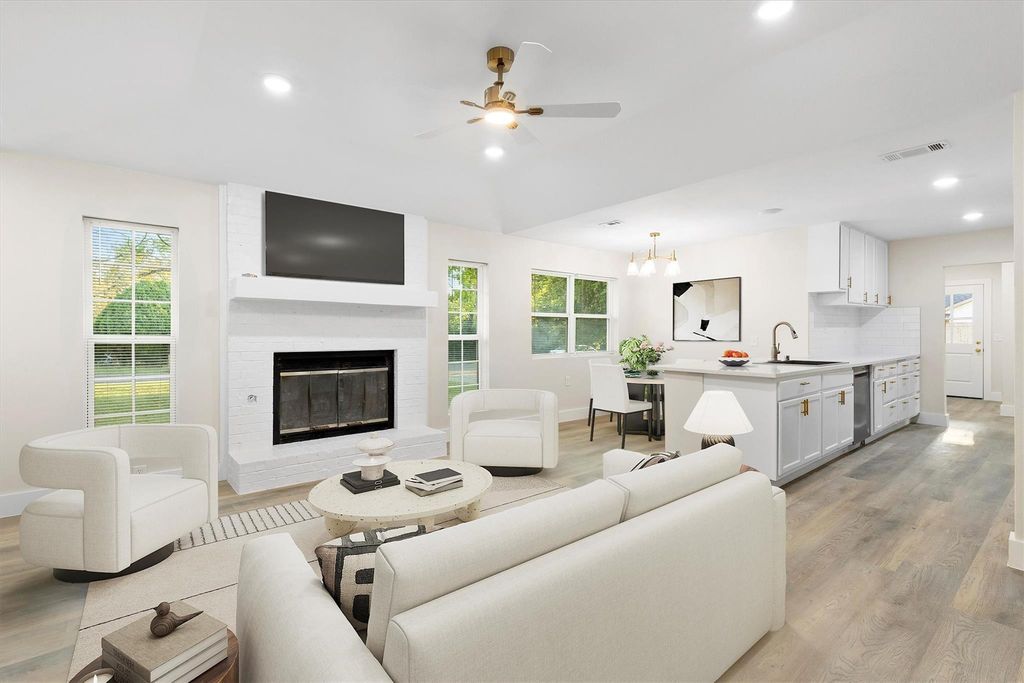 Living area featuring light wood-style floors, recessed lighting, a chandelier, a fireplace, and a ceiling fan