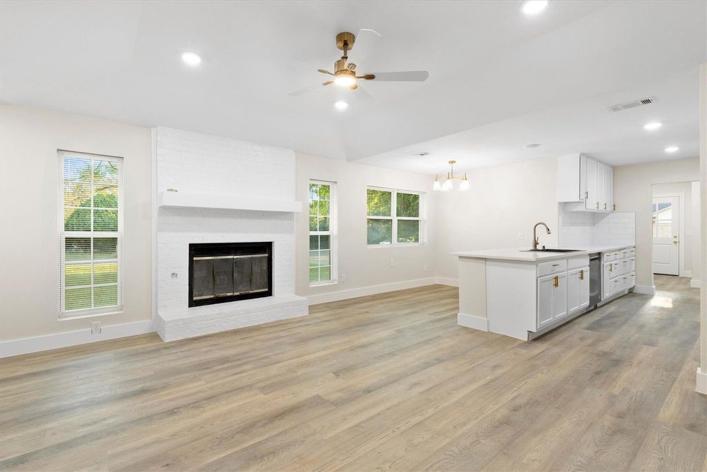 Unfurnished living room with recessed lighting, light wood-style flooring, a brick fireplace, a ceiling fan, and a chandelier