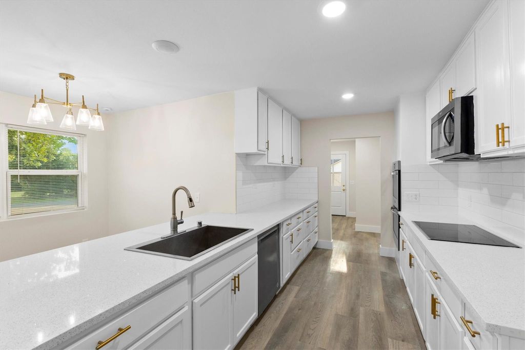 Kitchen with white cabinets, plenty of natural light, light stone countertops, and recessed lighting