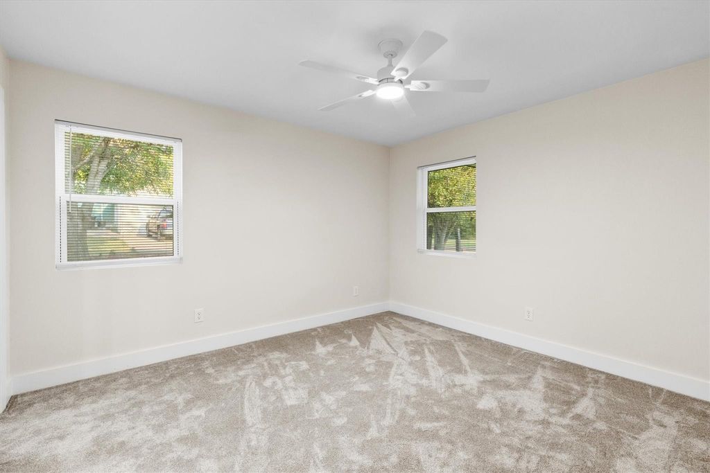 Carpeted empty room with baseboards and a ceiling fan