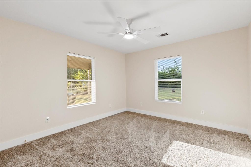 Empty room featuring light carpet and a ceiling fan