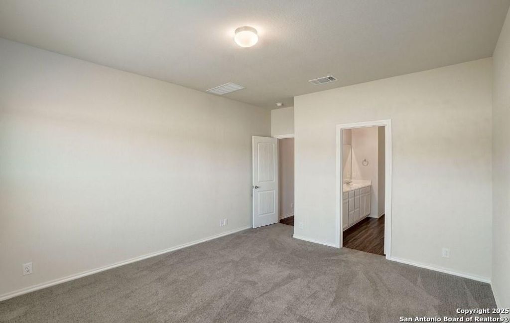 Unfurnished bedroom with dark carpet and connected bathroom