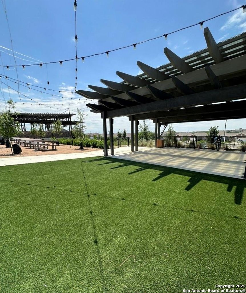 View of community featuring a lawn and a pergola