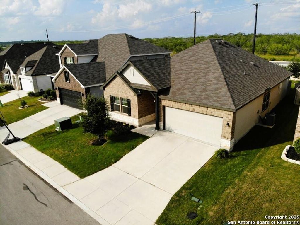 French country style house with an attached garage, concrete driveway, roof with shingles, and brick siding
