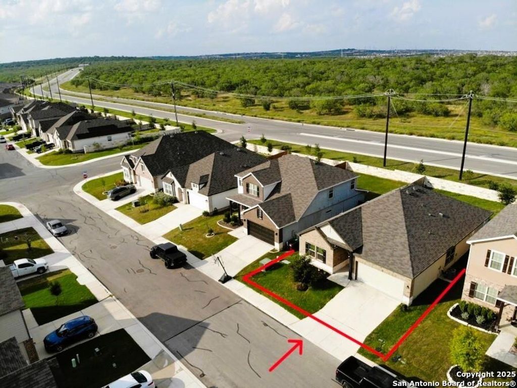 Aerial view of residential area featuring property boundaries highlighted and a forest