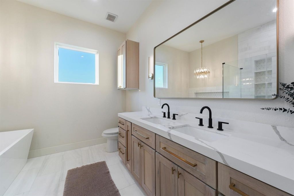 Primary bathroom with dual vanities, quartz countertops, and sleek black fixtures. 