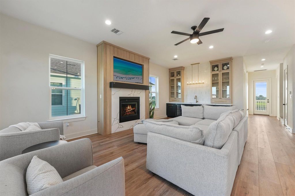 Bright living area featuring a quartz fireplace with white oak fluting, built-in shelving, and modern ceiling fan.