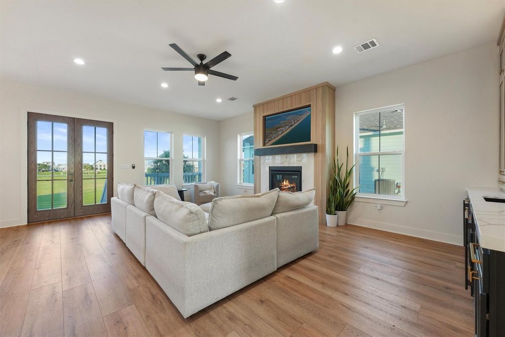 Spacious seating area with abundant natural light, French doors to balcony, and contemporary fireplace centerpiece.  