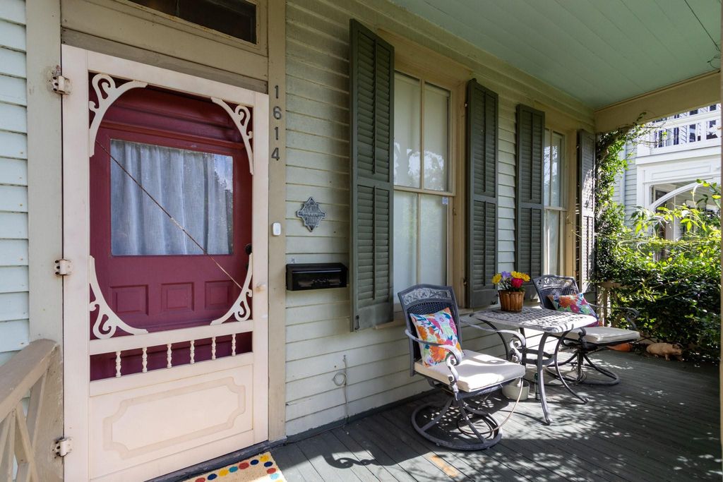 Circa 1886, front porch of 1614 Ball with its original wood shutters and 1900 Storm Survivor medallion. Above the front door is a screened transom.