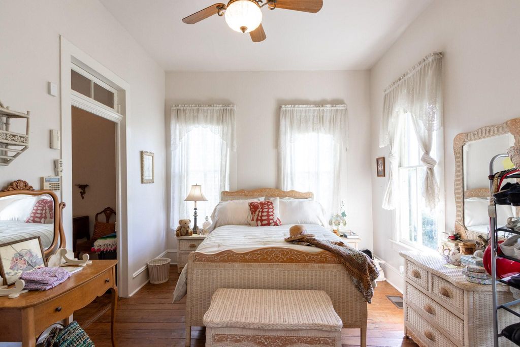 Timeless front downstairs bedroom photo with front window on right looking onto the front porch. Beautiful wood floors, 12" baseboards with toe-molding. Transom over doorway leading to 2nd bedroom. 