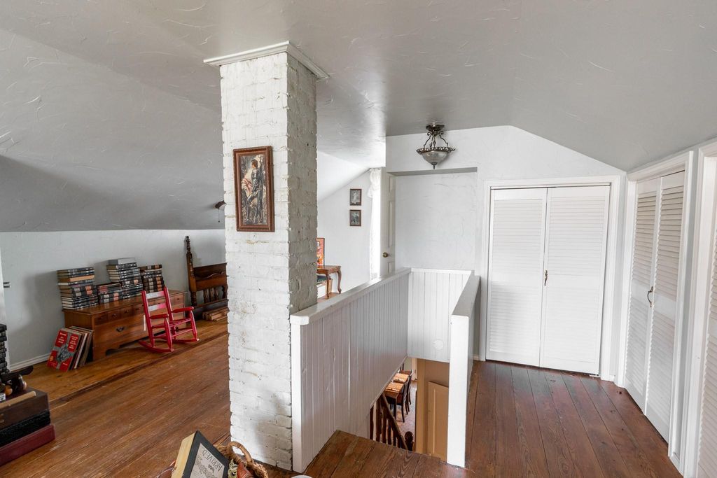 View of the staircase coming up to the second floor. Lots of closet space. Painted brick chimney in the foreground. Original wood floors. 