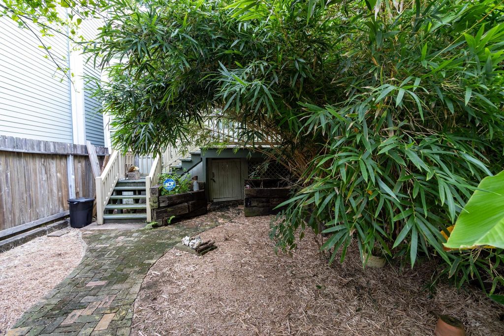From the back porch there is a brick path to the underneath of the raised cottage and the brick path continues to the alley gate. 