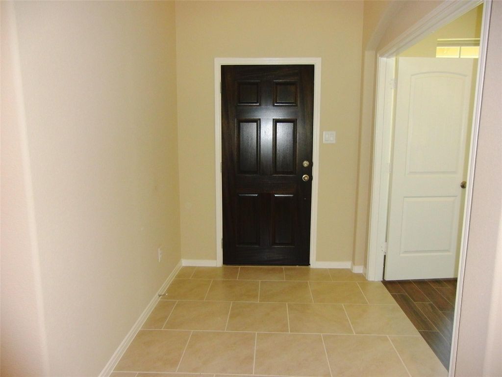 A welcoming entrance featuring elegant tile flooring and a stylish dark wood door sets the tone for the rest of the home.
