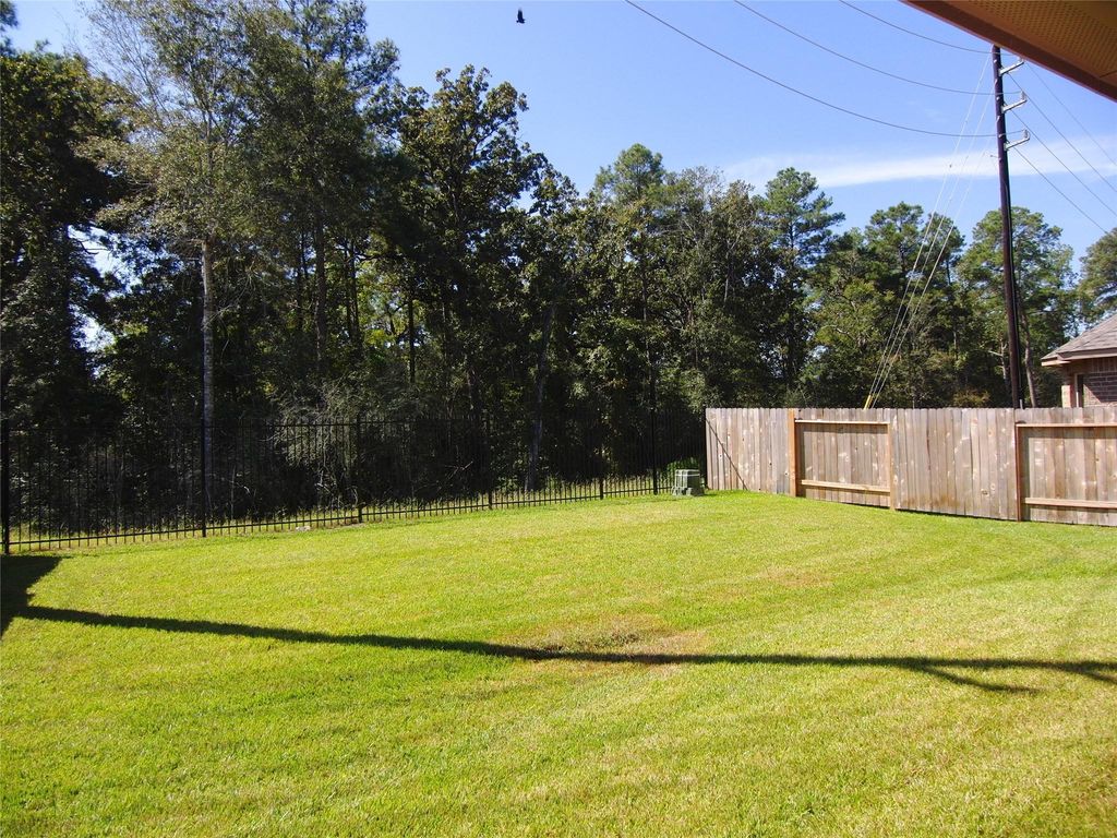 The backyard is surrounded by tall trees from a greenbelt, providing a natural, serene backdrop for privacy and relaxation.