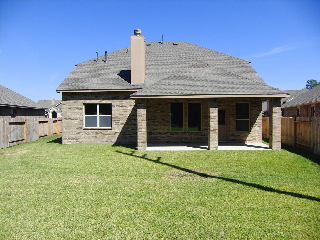 Covered patio area with a gas connection for grill. The yard is enclosed by a wooden fence, providing privacy and space for outdoor activities.