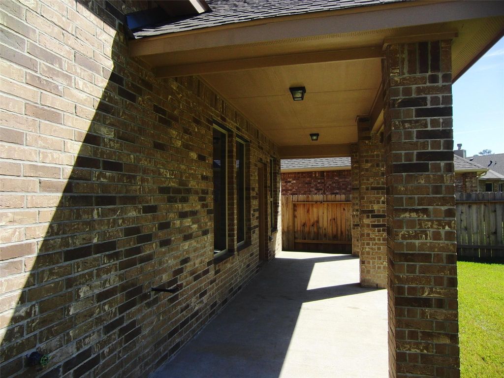 Covered patio area providing a shaded space ideal for outdoor relaxation. The patio leads to a fenced backyard, offering privacy.