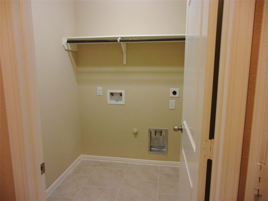 Efficient utility room with hookups for laundry machines and convenient shelving for storage.