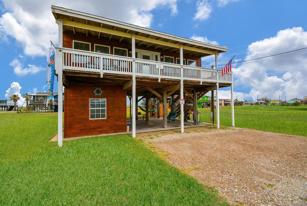 4407 Bluewater a charming wooden exterior, spacious front and back deck and open ground level for parking or outdoor activities. Surrounded by a lush green lawn of 2 lots, perfect for coastal living.