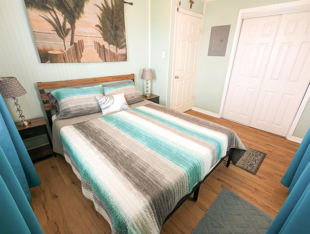 This bedroom features a beach-themed decor with a queen-sized bed, and ample closet space. Light pastel walls and a large beach painting create a relaxing atmosphere.