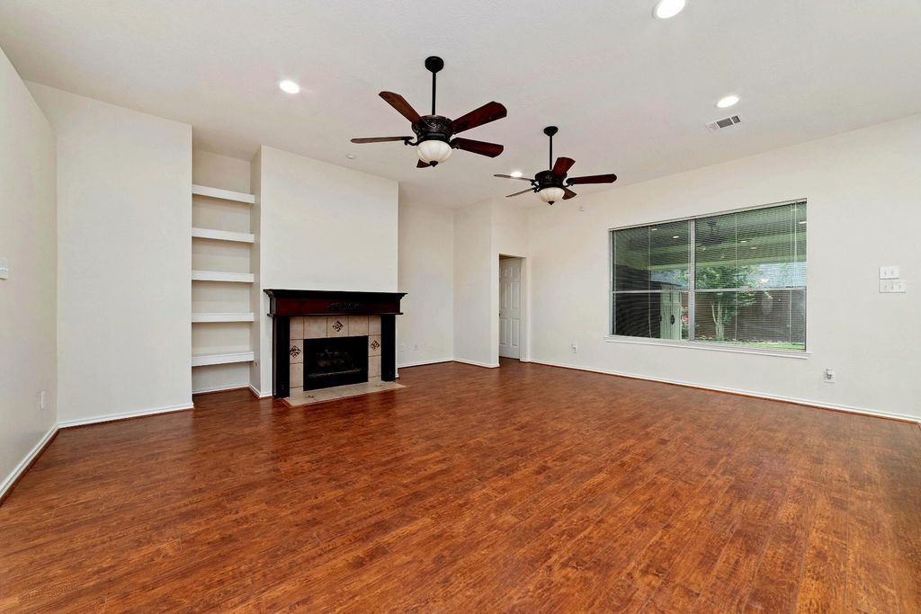 As the warmth of the floors flows beneath you, your space is beautifully accented by a striking cherry wood mantel framed with elegant tile surround. Soft canister lighting highlights the mantel’s details, creating a cozy and inviting atmosphere. Timeless ceiling fans blend classic design with modern functionality, perfectly complementing the room’s sophisticated style.