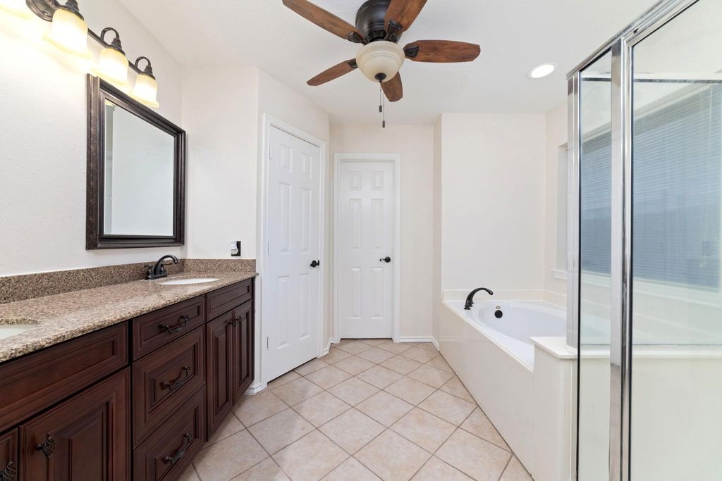 Open and airy primary bathroom featuring elegant cherrywood finishes, abundant natural light, and direct access to a spacious walk-in closet.     