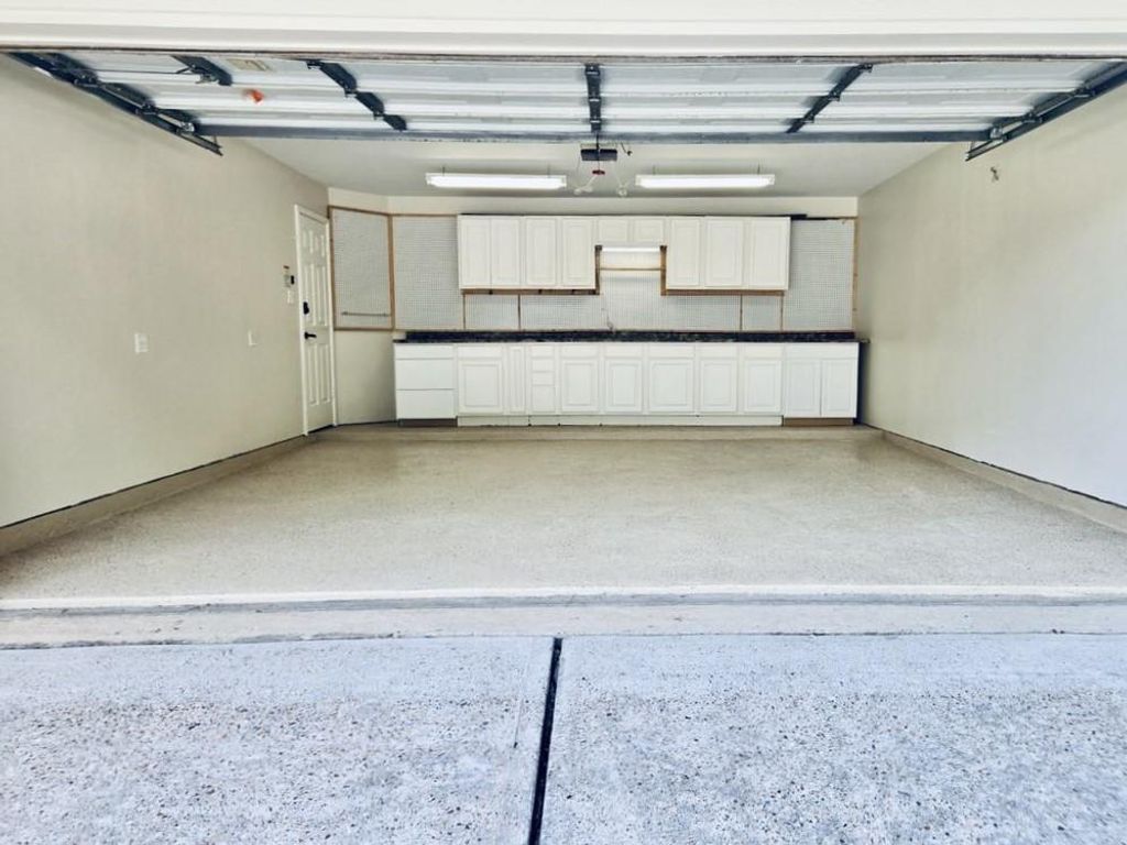 This home features a spacious, well-organized garage complete with custom cabinetry, a durable countertop workspace, and upper shelving — perfect for all your storage and project needs.